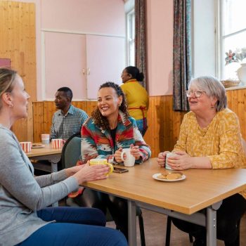 Mensen kletsen en drinken koffie in buurthuis