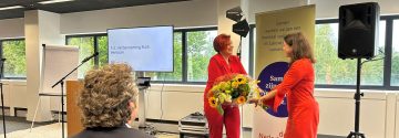 Ruth Peetoom neemt bloemen in ontvangst tijdens de ALV