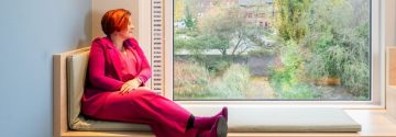 Ruth zit op een vensterbank in ggz instelling en kijkt naar buiten