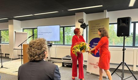 Ruth Peetoom neemt bloemen in ontvangst tijdens de ALV