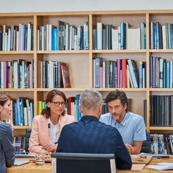 Vier mensen aan tafel bij boekenkasten