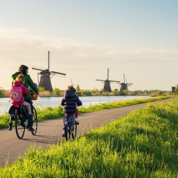 Vrouw fiets met kinderen door Nederlands landschap