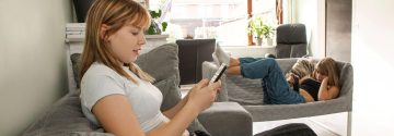 Twe tieners zitten op hun telefoon op de bank
