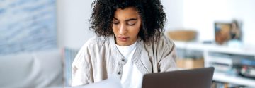 Vrouw achter laptop bezig met papieren