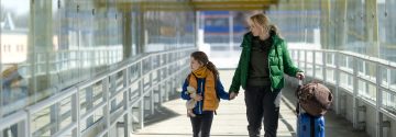 Vrouw met dochter lopen met koffer