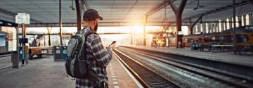 Man wacht op de trein en kijkt op telefoon