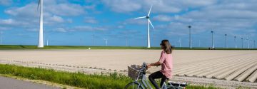 Vrouw fiets op weg met windmolens