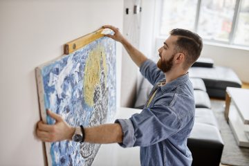 Man hangt schilderij op