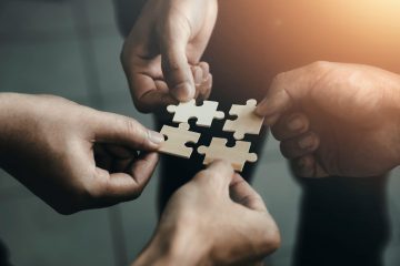 Handen die puzzelstukjes samen brengen
