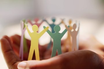 Papieren poppetjes die handen vast houden