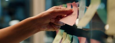 Hand plakt een sticky note op een glazen muur