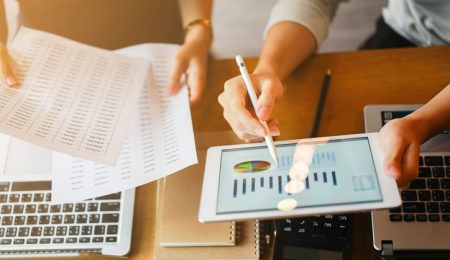 2 mensen alleen armen zichtbaar achter bureau met computer en rekenmachinei Stock 1138898580
