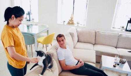 Man op bank, vrouw aait kat in huiskamer