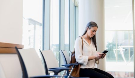 Vrouw zit in de wachtkamer op telefoon