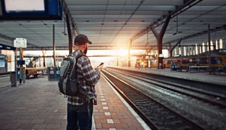 Man wacht op de trein en kijkt op telefoon