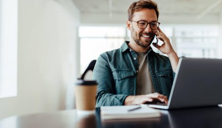 Man zit achter computer en lacht naar het scherm