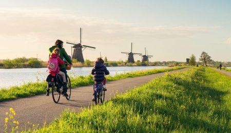 Vrouw fiets met kinderen door Nederlands landschap