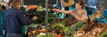 Man koopt groente bij marktkraam