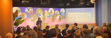 Vrouw spreekt mensen toe in een zaal