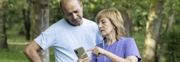 Ouder stel met smartphone en oortjes in de natuur
