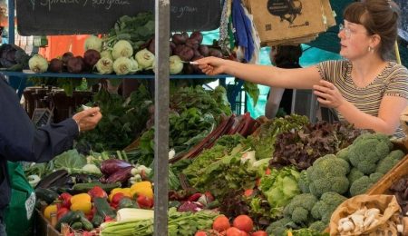 Man koopt groente bij marktkraam